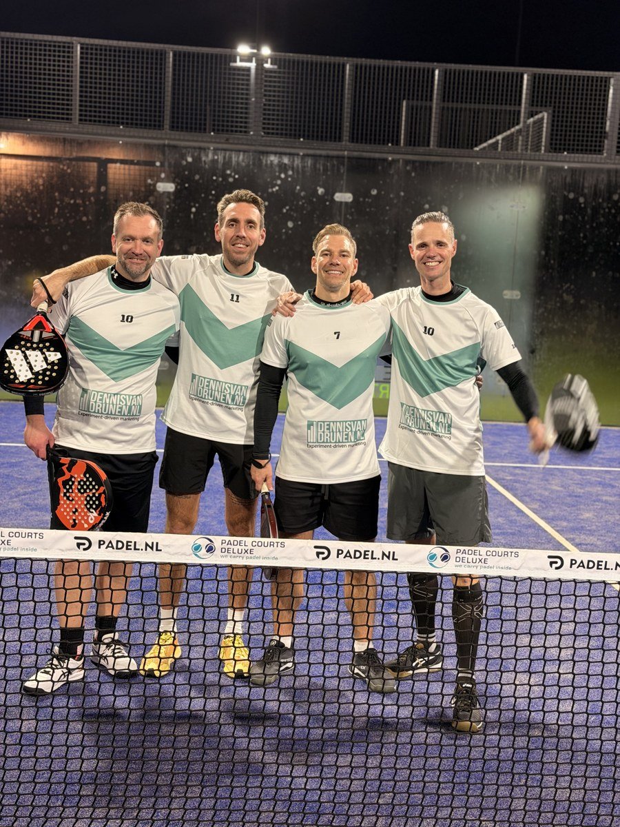 Vier padelspelers in teal-witte shirts bij het net; Dennis staat tweede van rechts